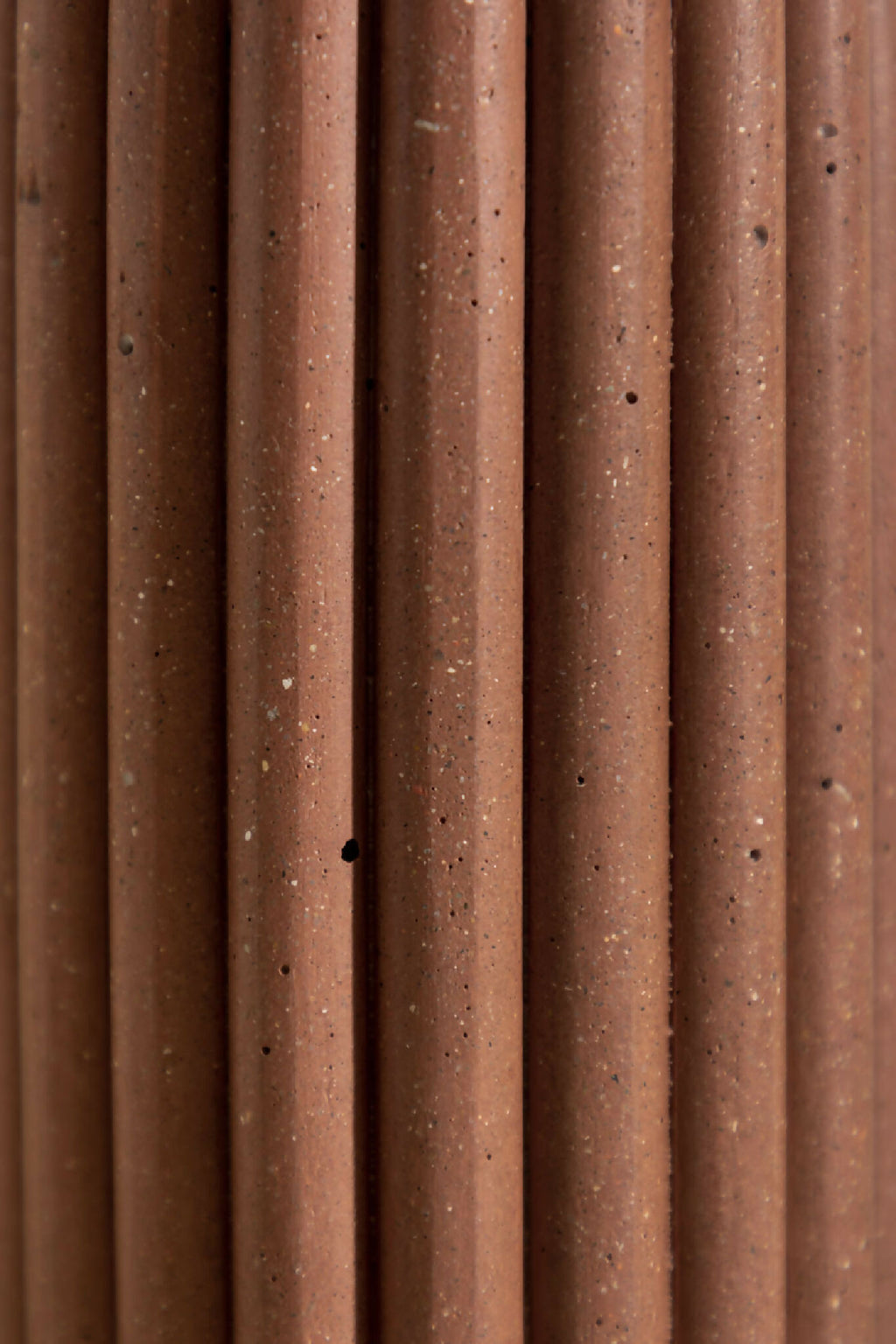 Vase en céramique brune, gros plan sur les stries verticales et les points.