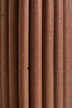 Vase en céramique brune, gros plan sur les stries verticales et les points.