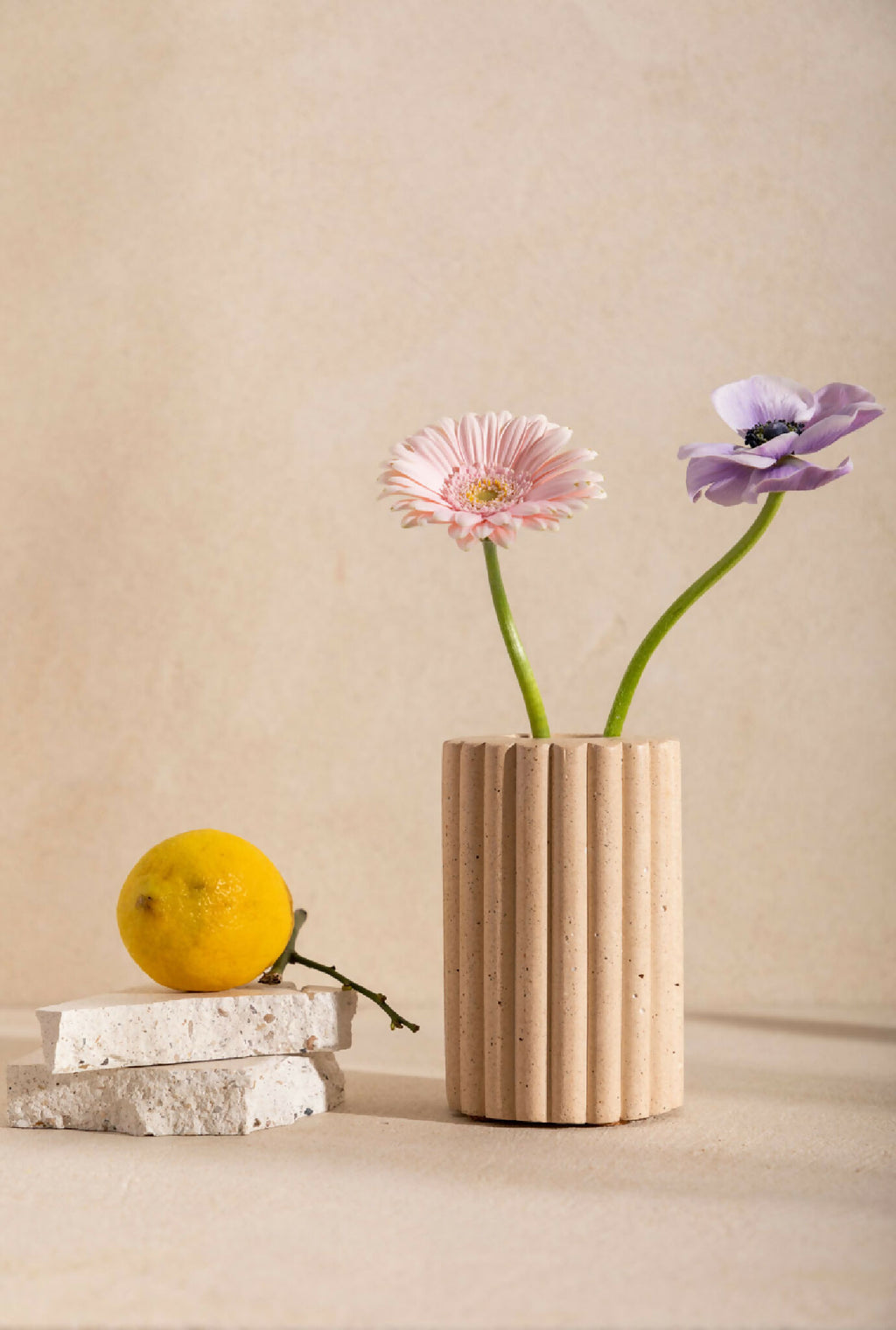 Vase en céramique beige striée, avec bouquet de fleurs roses et violettes.