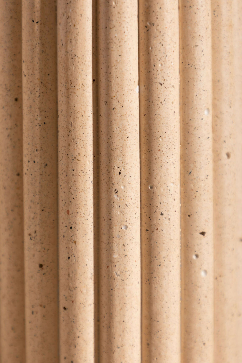 Vase en céramique beige texturée, stries verticales avec grains visibles.