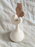 Vase en céramique blanche avec feuilles brunes séchées et tige centrale