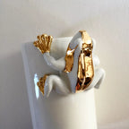 Vase en forme de grenouille blanc, figurine dorée sur le corps.