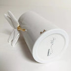 Vase blanc, base circulaire avec inscription, libellule dorée sur une aile.