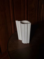 Vase blanc nervuré, côtés droits et bord supérieur ondulé, vue de profil.