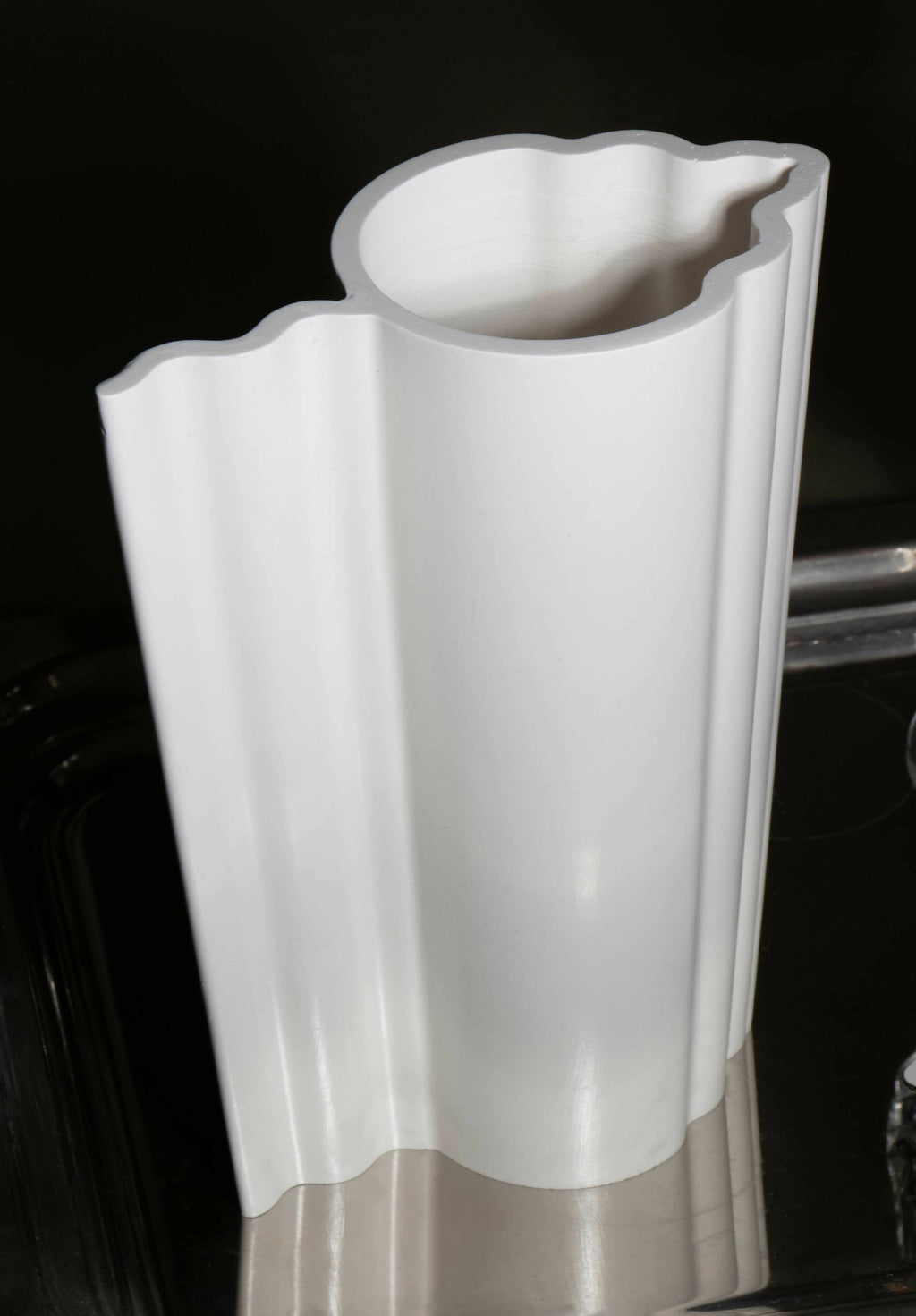 Vase blanc à profil nervuré avec bord supérieur évasé et ondulé, vue rapprochée.