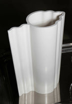 Vase blanc à profil nervuré avec bord supérieur évasé et ondulé, vue rapprochée.