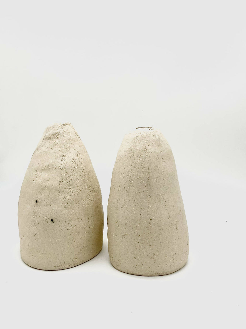 Deux vases coniques DUO beige, texture granuleuse et ouvertures noires en haut.