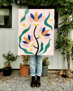 Peinture acrylique sur toile carrée posée dehors : fleurs stylisées orange, bleues et vertes