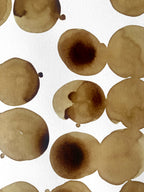 Taches de café brunes sur papier, formes circulaires superposées.