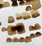 Peinture au café en gros plan, taches brun foncé et beiges, signature discrète