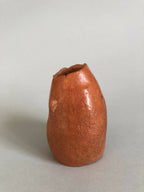 Petit vase en terre cuite orange, vue de côté, texture irrégulière.