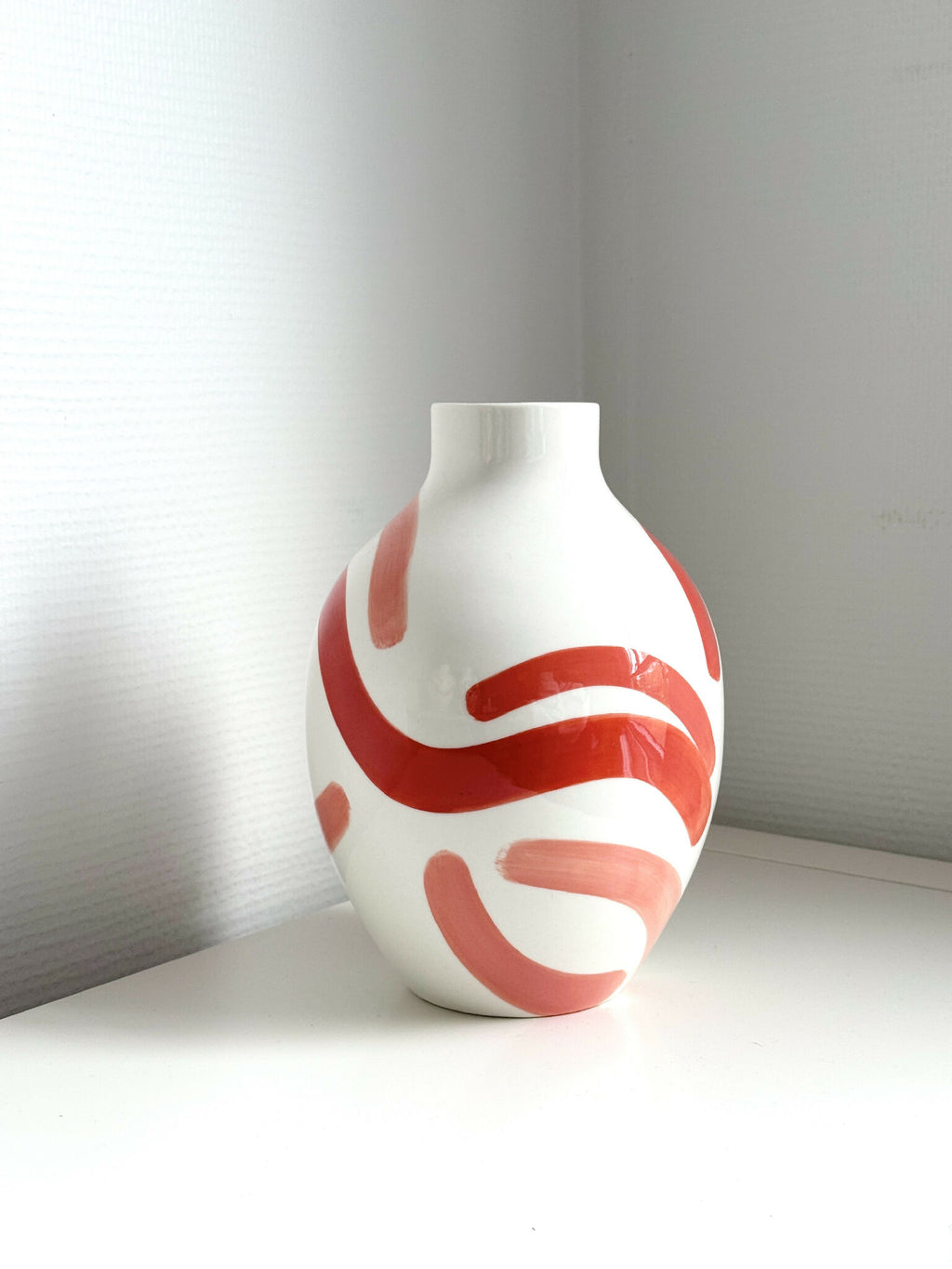 Petit vase buste blanc avec motifs abstraits rouge corail sur le devant.