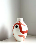 Petit vase buste blanc avec visage rouge corail, œil noir et forme arrondie.