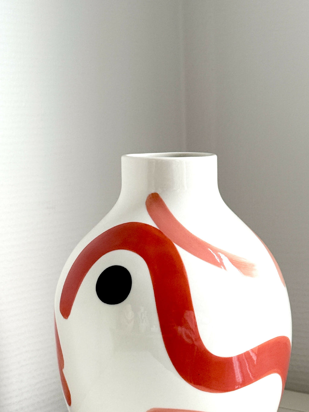 Petit vase buste blanc en céramique, gros plan sur motif rouge et œil noir