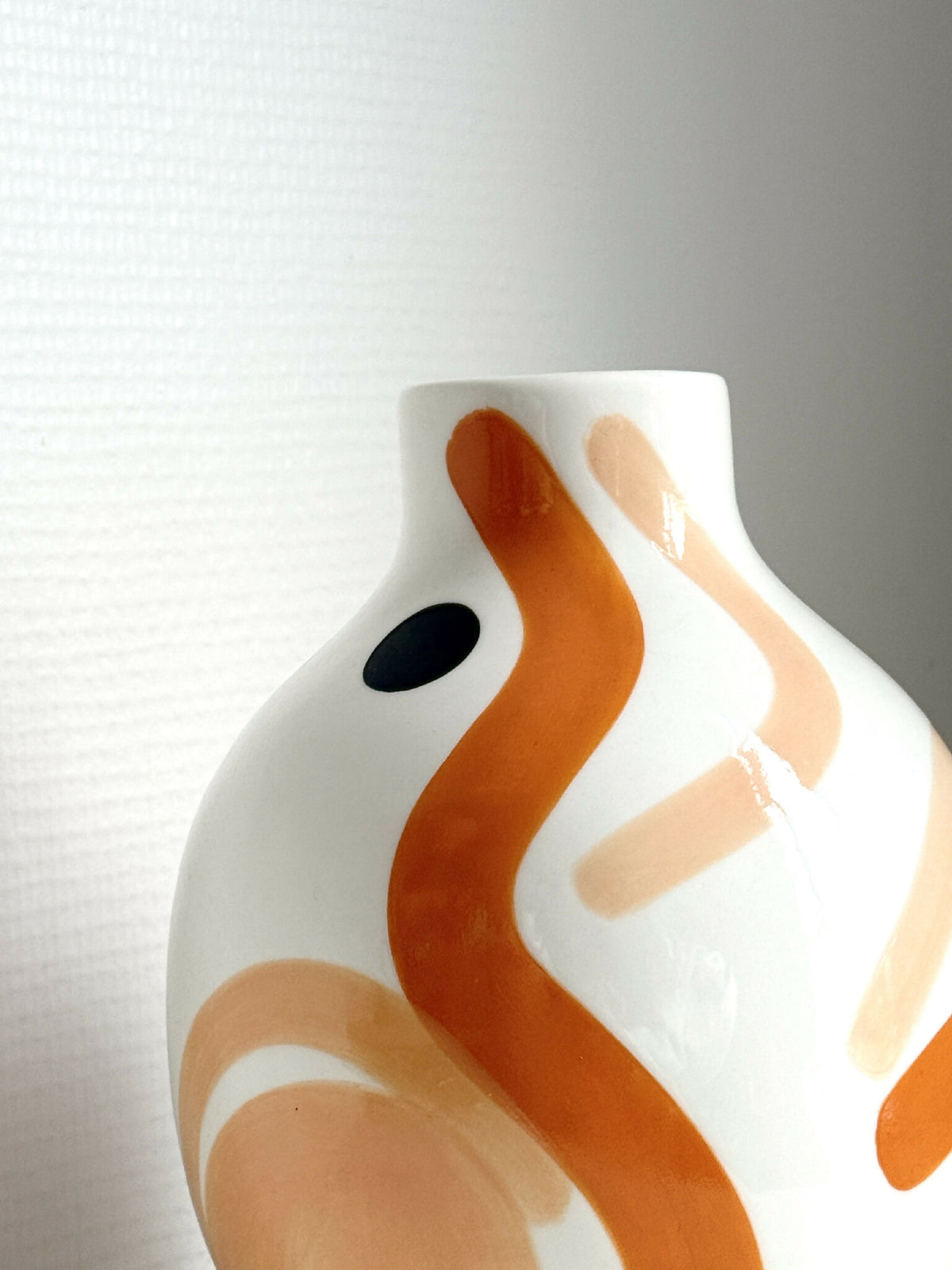 Petit vase buste blanc en céramique, gros plan sur motif ocre et œil noir