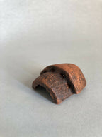 Petite pièce en cuivre rouillé ajourée, cavité concave, vue inclinée.