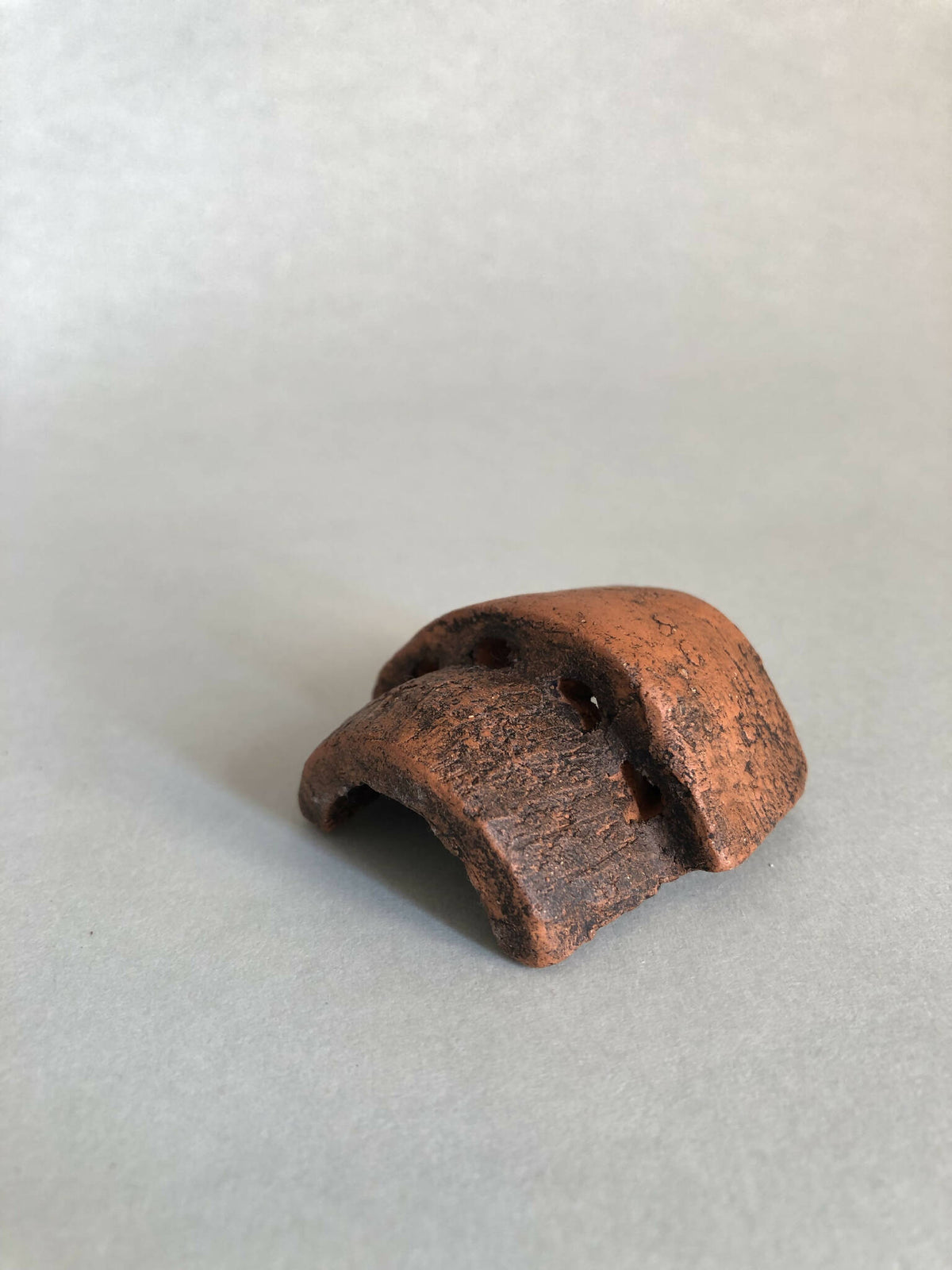 Petite pièce en cuivre rouillé ajourée, cavité concave, vue inclinée.