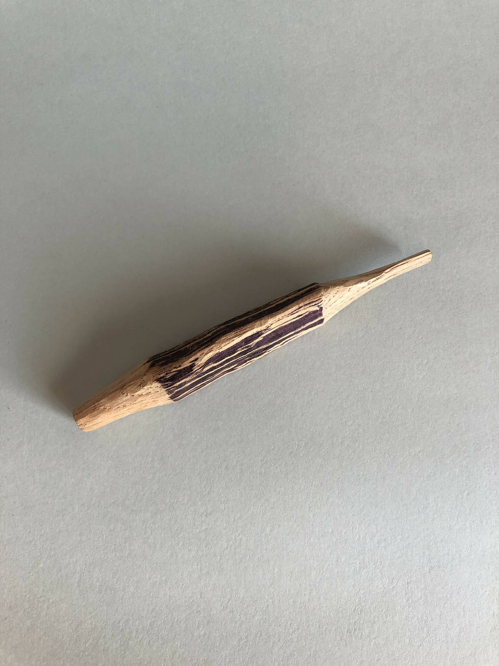 Petite forme en bois peinte, baguette allongée vue de côté, rayures sombres
