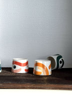 Petites tasses trapèze en céramique, motifs abstraits orange et crème, anse.