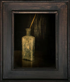 Bouteille ancienne en verre teinté jaune, tige dorée sortant du bouchon, dans un cadre.