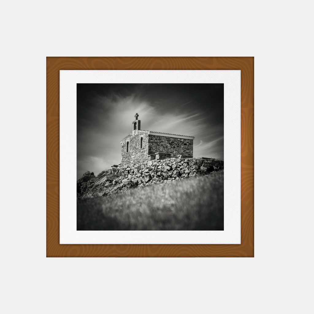 Photographie noir et blanc encadrée, chapelle de pierre sur une colline.