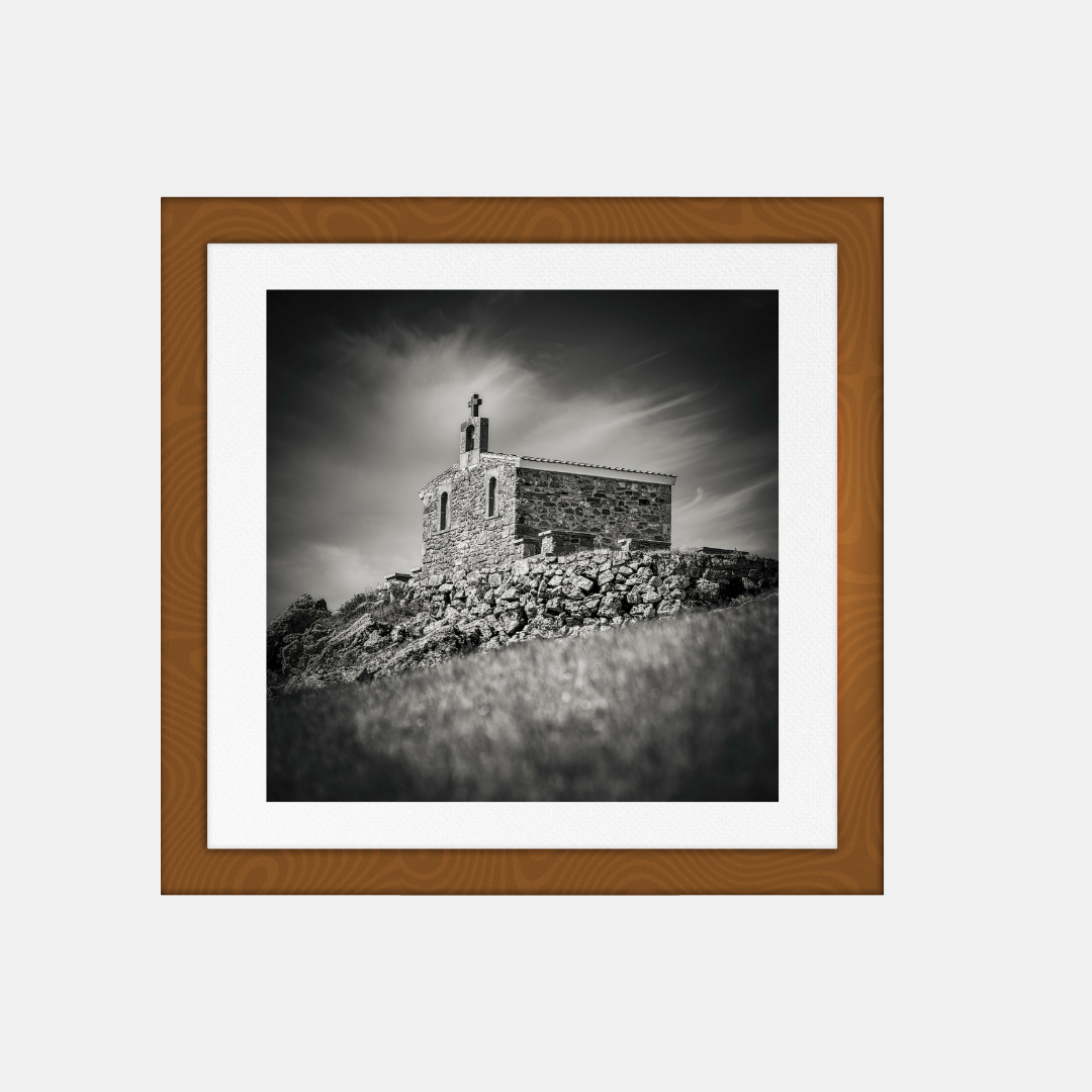 Photographie noir et blanc encadrée, chapelle de pierre sur une colline.