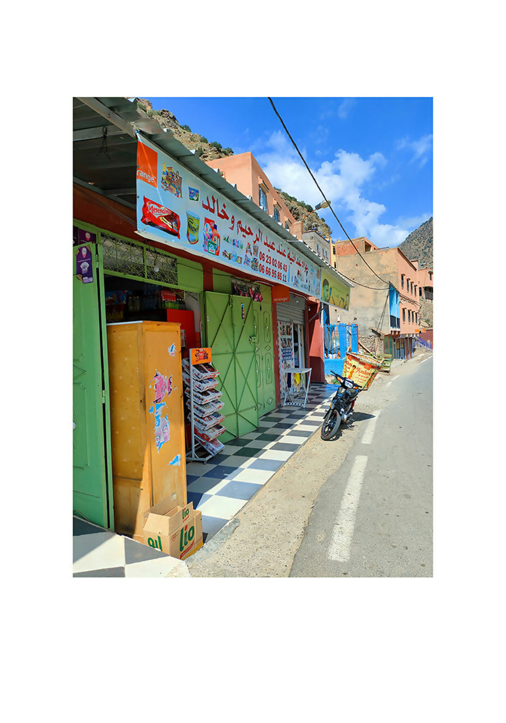 Photo de ruelle, façade verte et panneaux rouges, sol à carreaux