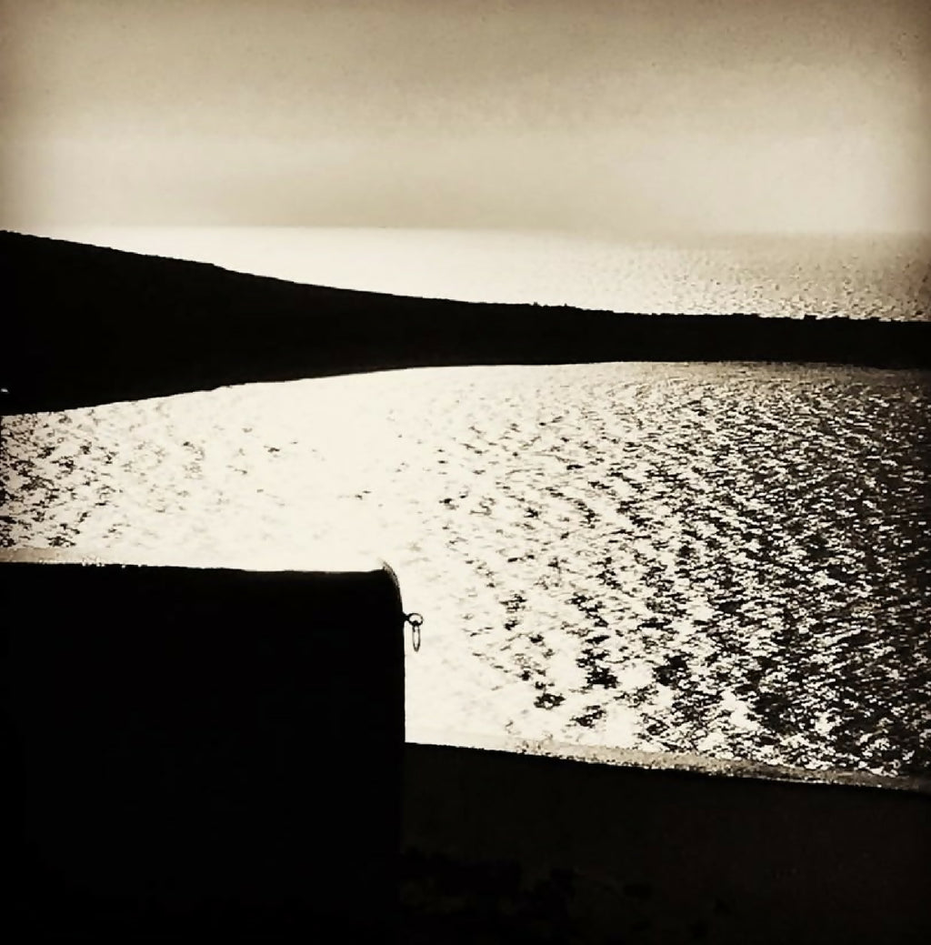 Livre de photographies : mur noir et route granuleuse, éclairage blanc au sol.