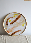Plateau rond à motifs abstraits, fond blanc cassé, jaune et brun