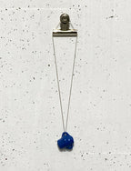 Pendentif en porcelaine bleue sur chaîne en argent avec fermoir métallique.
