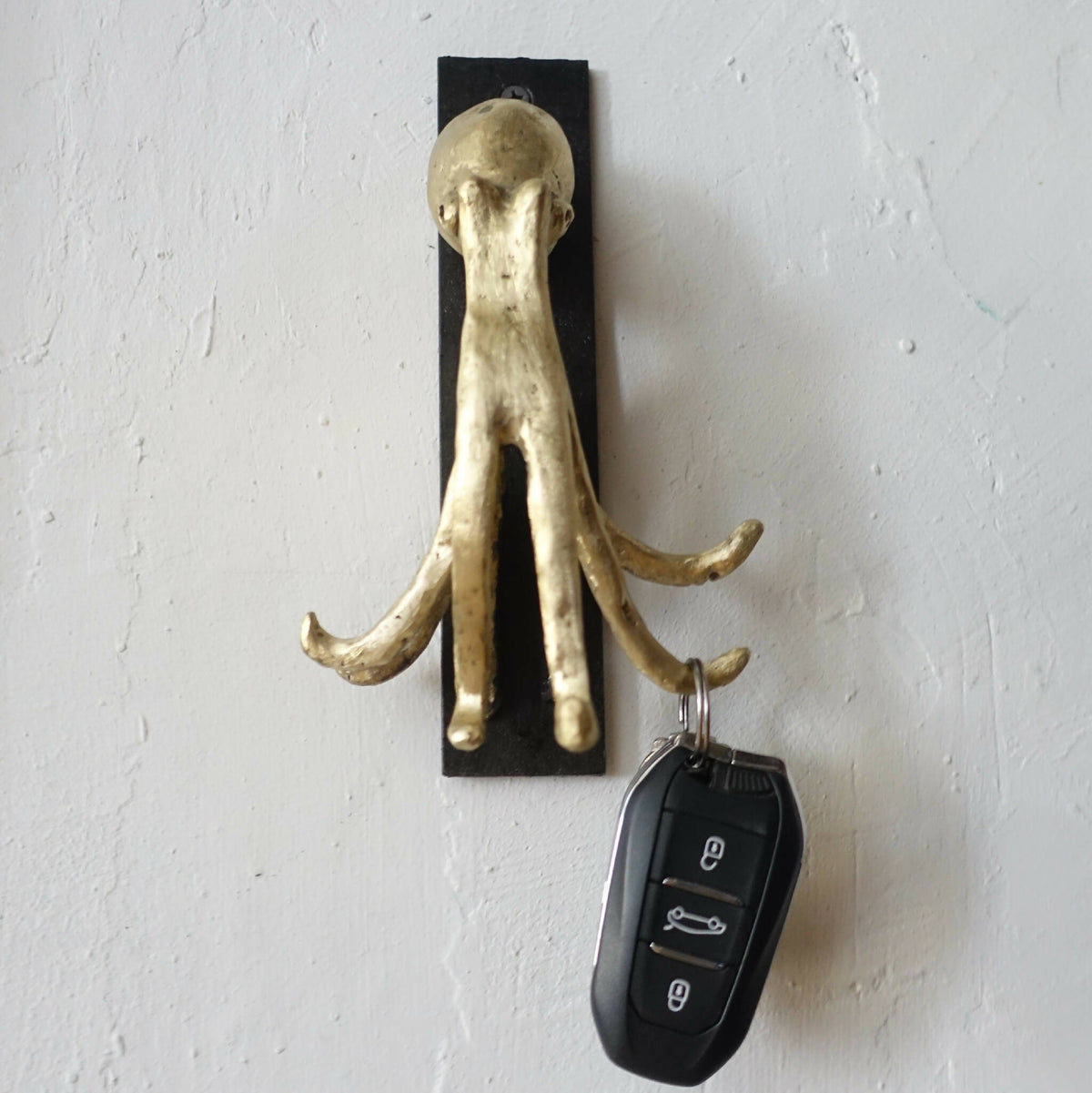Porte-clés figurine pieuvre dorée avec télécommande noire pendante