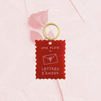Porte-clés rouge « Une pluie de lettres d’amour » sur anneau doré.