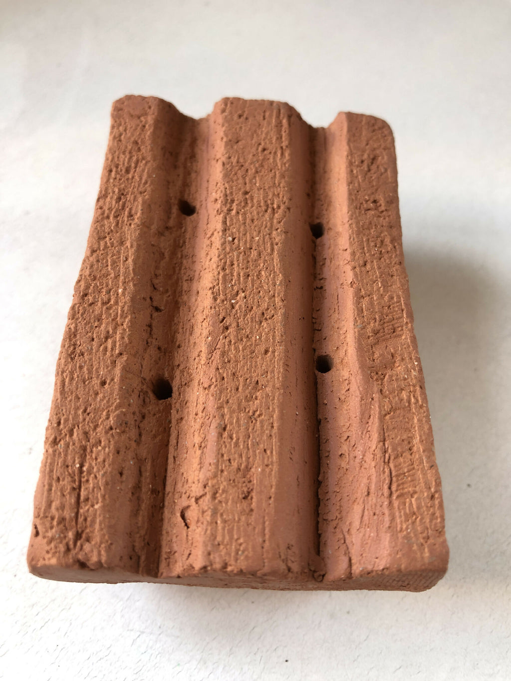 Porte-savon en terre cuite brun, face texturée avec rainures et trous de drainage