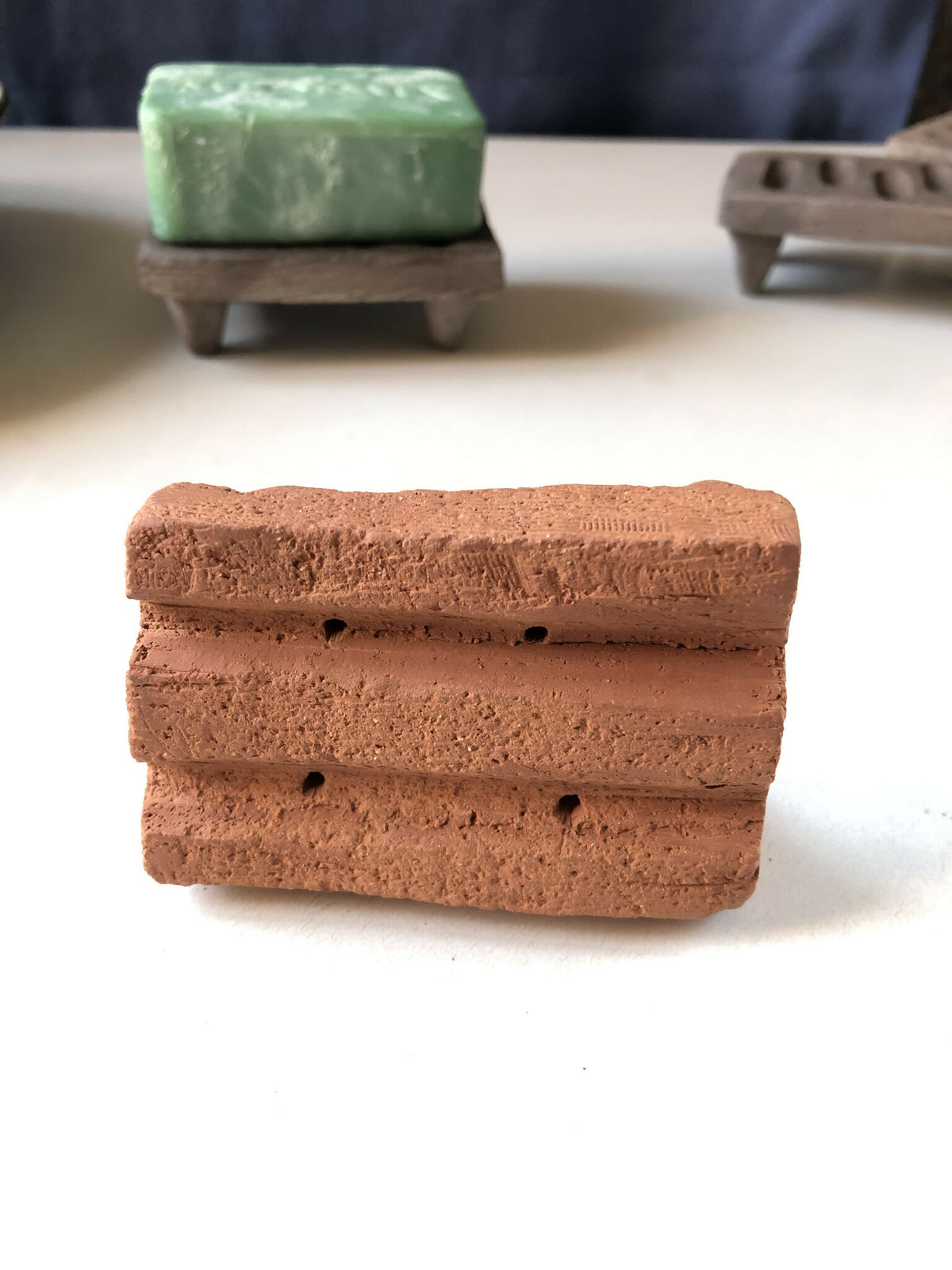 Porte-savon en terre cuite brun, forme rectangulaire ajourée sur pieds