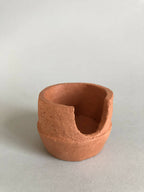 Petit pot en argile terracotta à ouverture latérale, intérieur creux.
