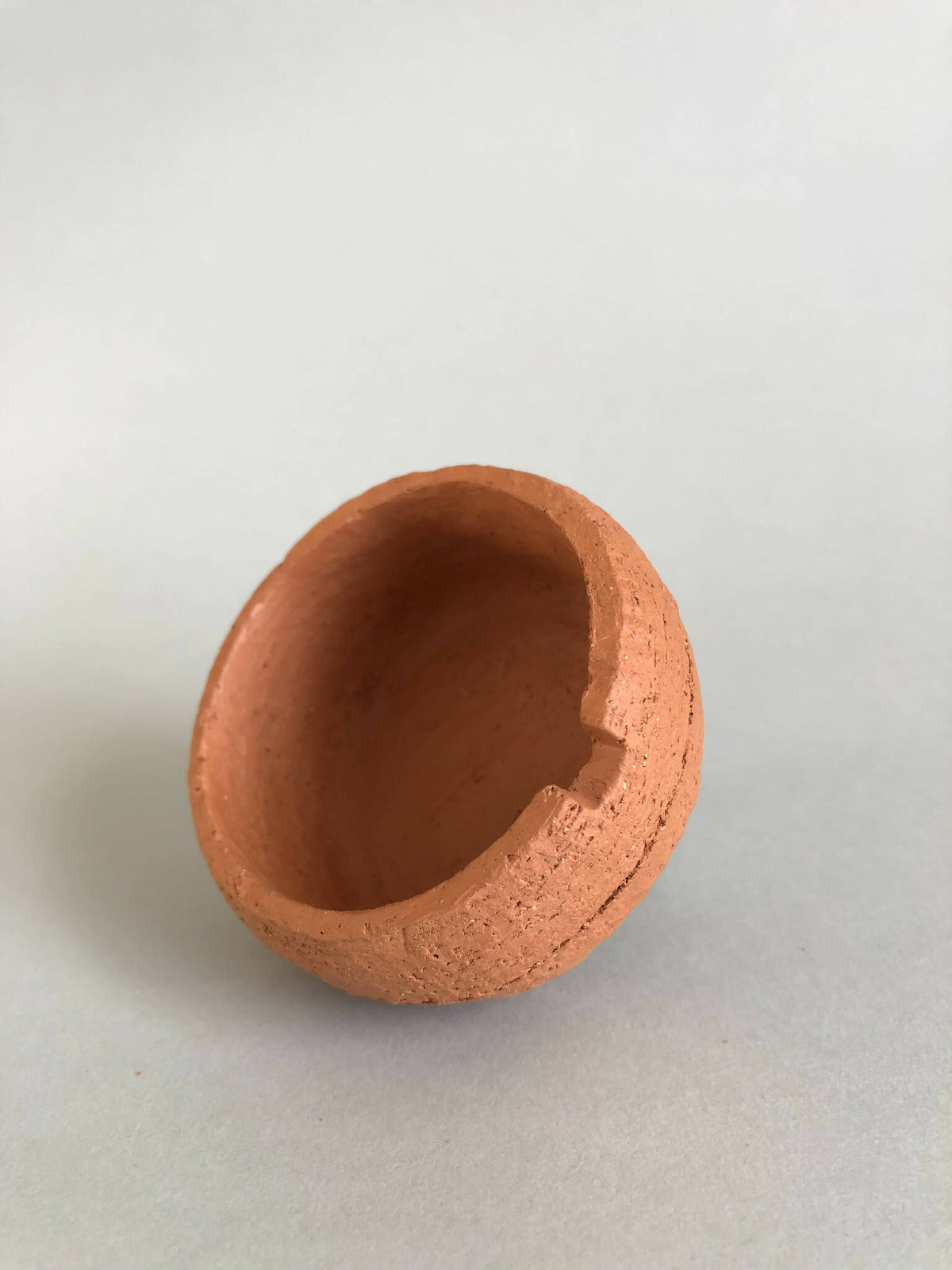 Petit pot en argile terracotta avec encoche sur le bord et ouverture ovale