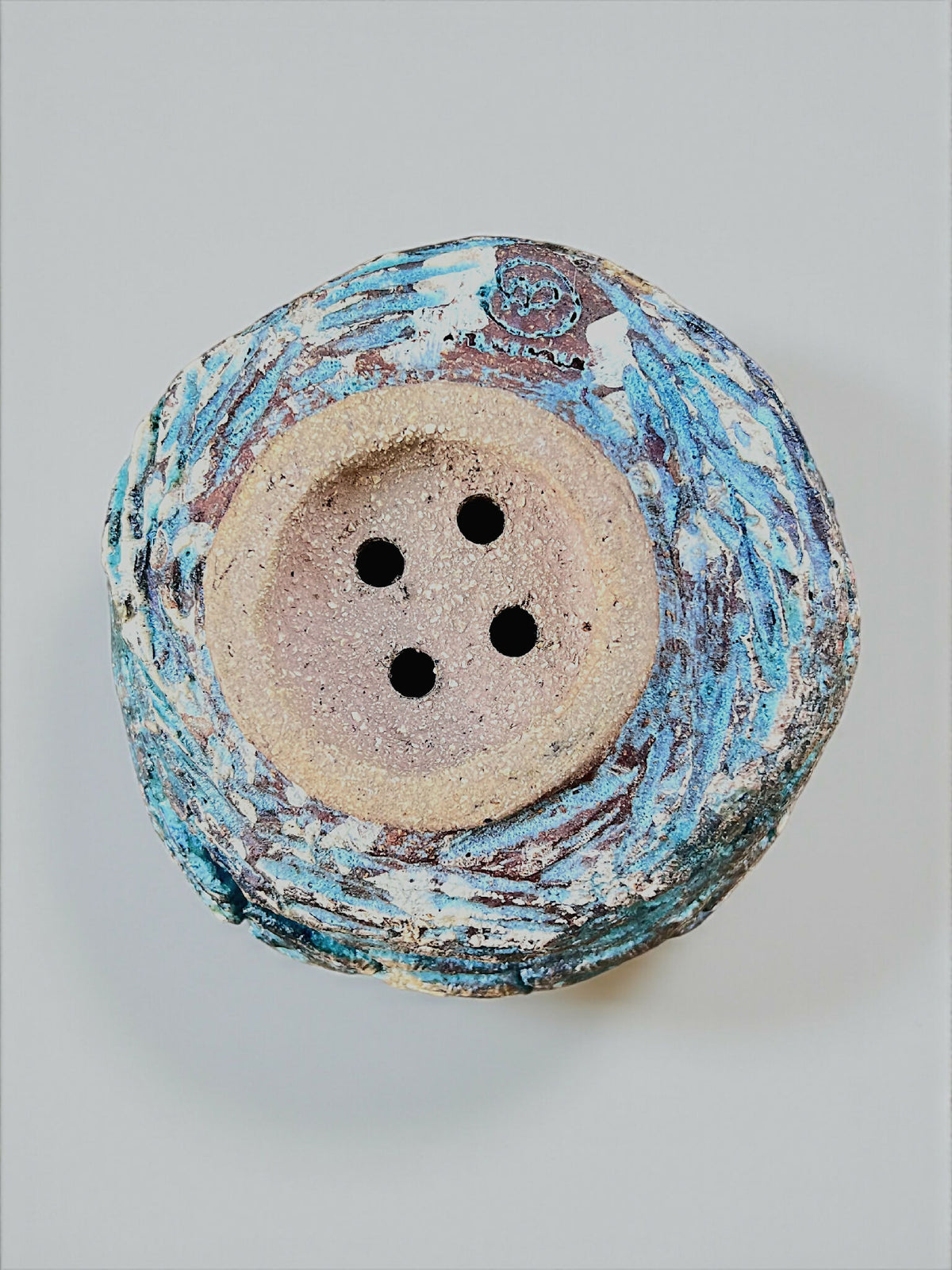 Base de pot en grès turquoise, intérieur brun, quatre trous de drainage bien visibles.