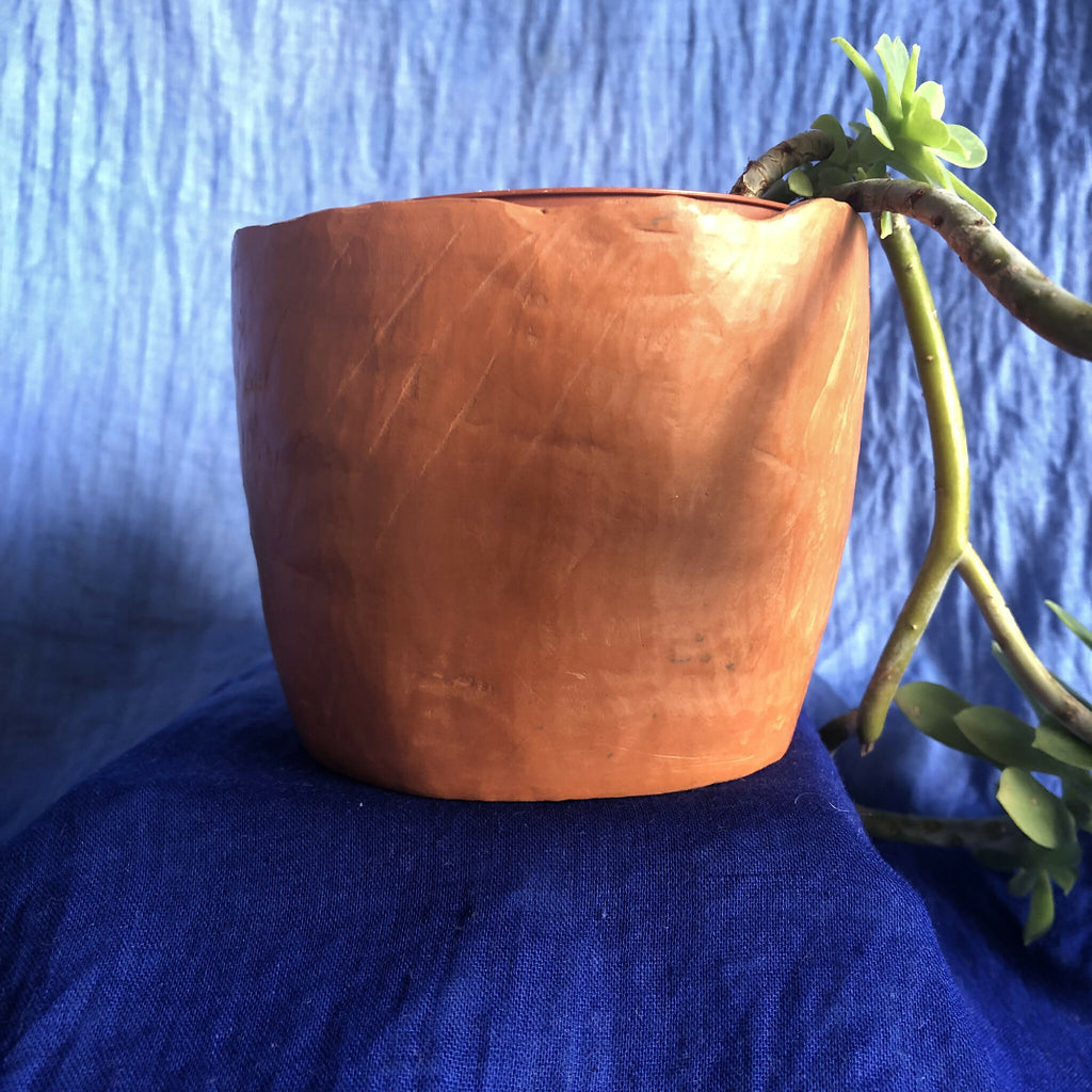 Pot en métal cuivré rouge, texture martelée et bord supérieur roulé.