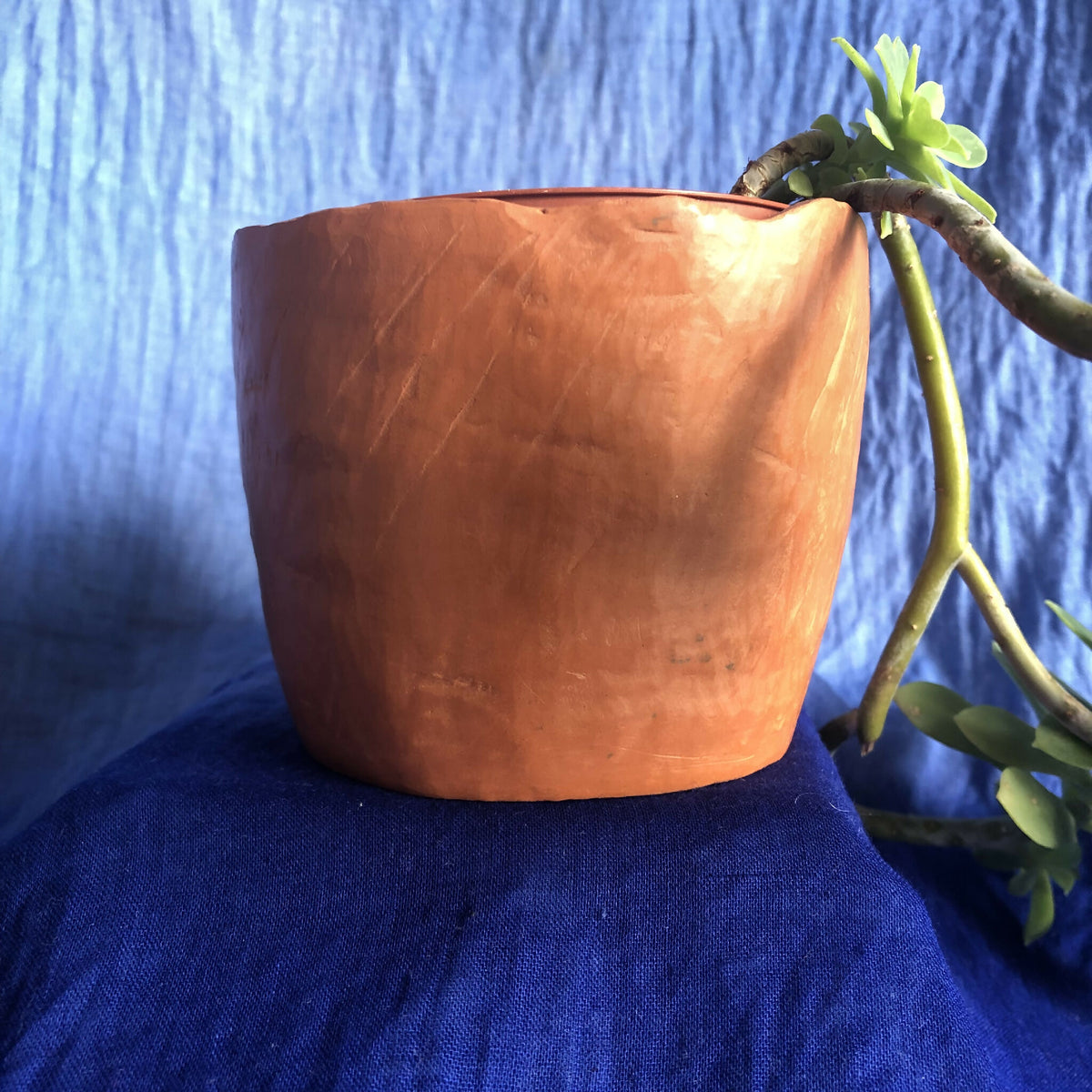 Pot en métal cuivré rouge, texture martelée et bord supérieur roulé.