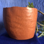 Pot en métal cuivré rouge, vue latérale rapprochée, texture martelée.