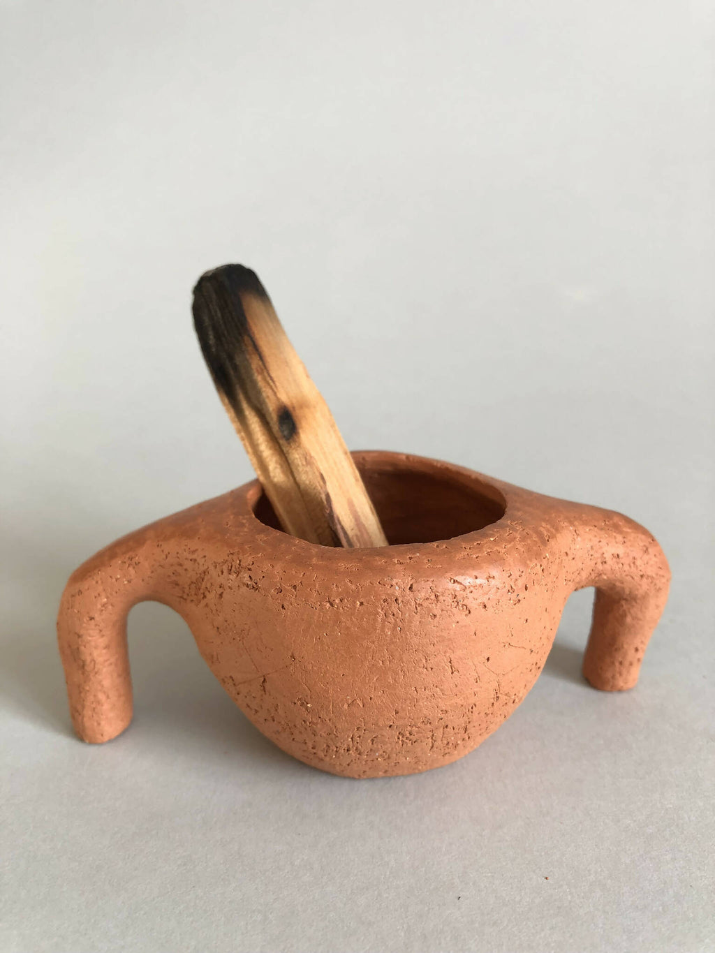 Pot en terre cuite orange à deux pattes, bol ouvert avec petit bâton