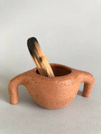 Pot en terre cuite orange à deux pattes, bol ouvert avec petit bâton