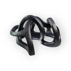 Sculpture abstraite en argile sombre, nœuds entrelacés et formes courbes.