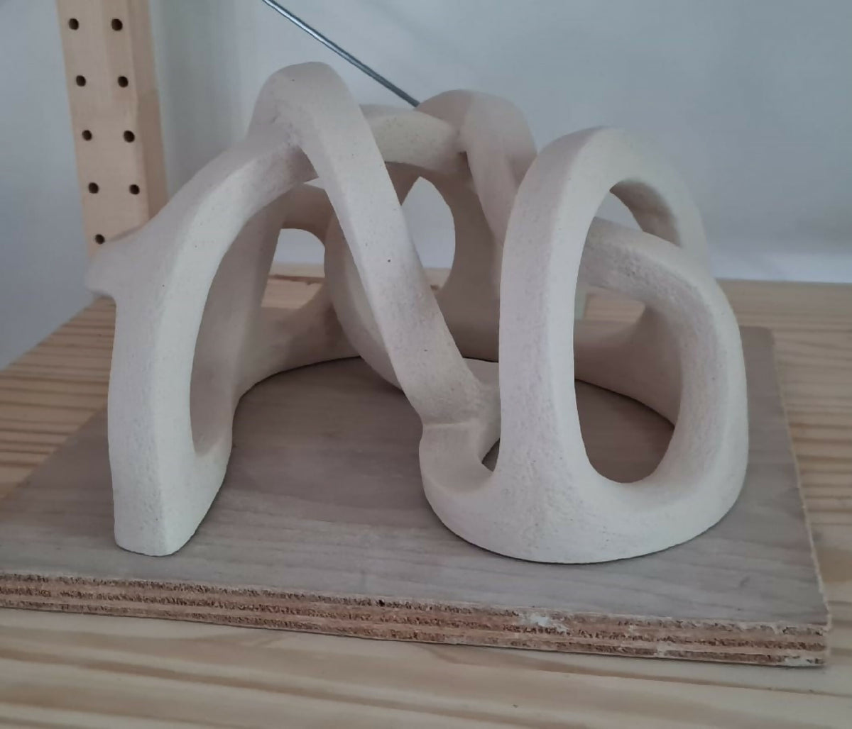 Sculpture abstraite en argile claire, nœuds entrelacés au fini mat.