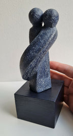 Sculpture couple bleu nuit, figurines l’une contre l’autre, sur socle noir