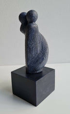 Sculpture couple bleu foncé, dos visible, sur socle cubique noir