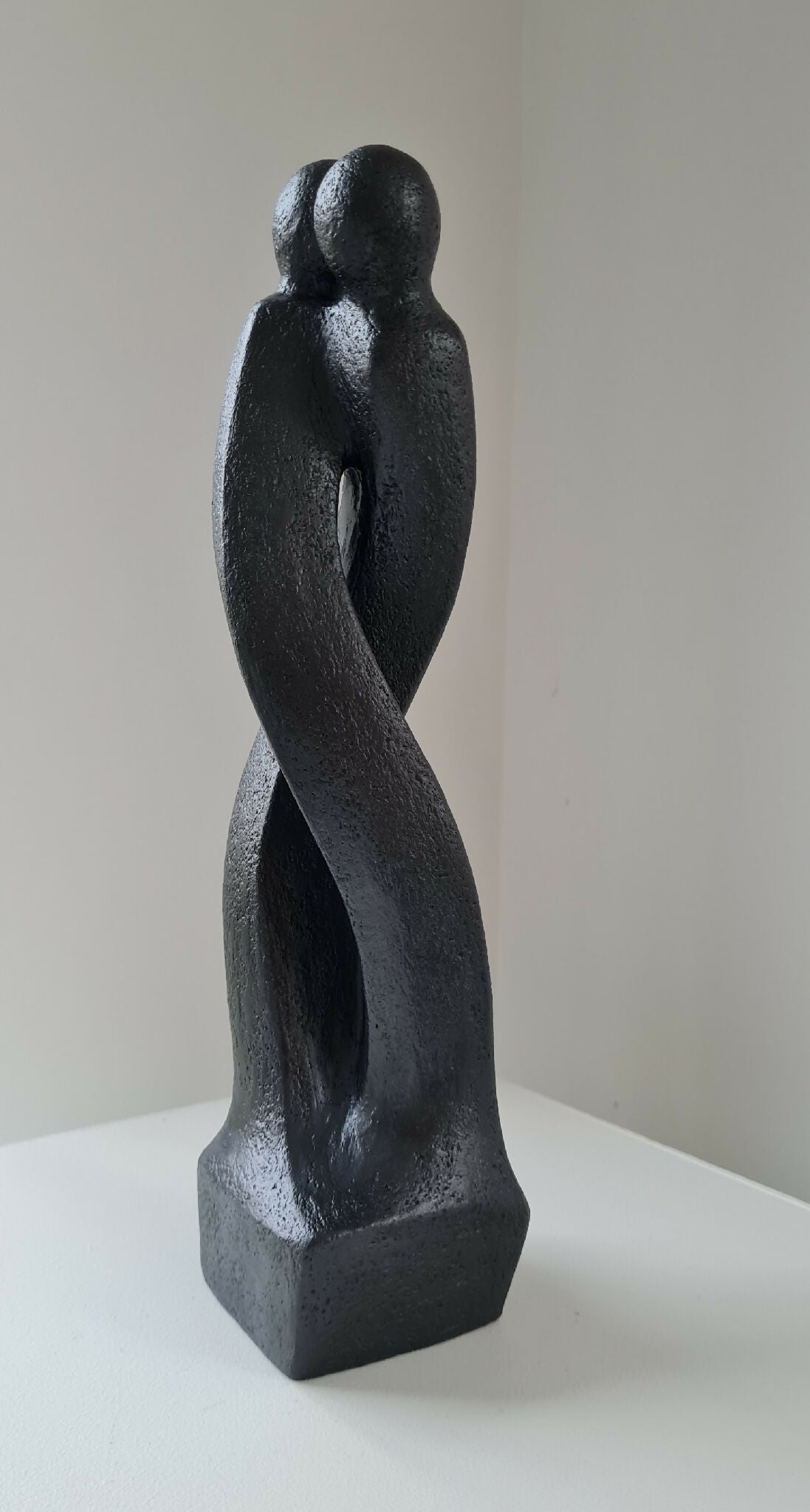 Sculpture en argile sombre de deux corps enlacés, posture debout