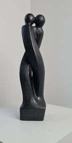 Sculpture en argile sombre : deux personnages enlacés de profil sur socle