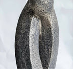 Sculpture en argile grise texturée, deux formes entrelacées avec ouverture en U.