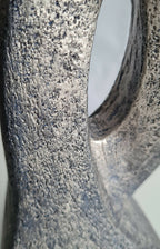 Sculpture en argile grise à surface granuleuse, bord d’ouverture ovale et creux.